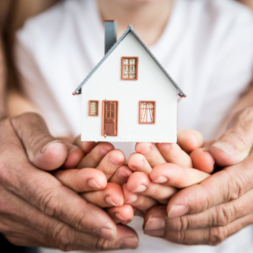 Famille du Var unissant leurs mains autour d'une maquette de maison, symbolisant l'unité lors des expertises immobilières pour successions, donations et divorces.